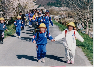 桜咲く土手を通学する小学生たち