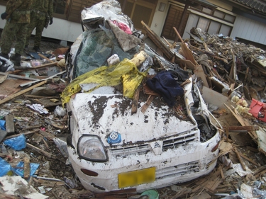 住宅前の被災車両とガレキ